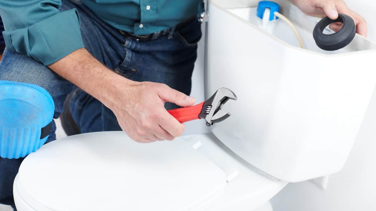 Plumber fixing a two-piece toilet